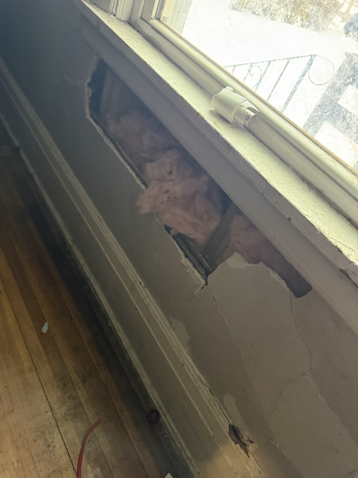Opened wall beneath a window exposing framing and insulation during structural investigation at 1205 Spring Street